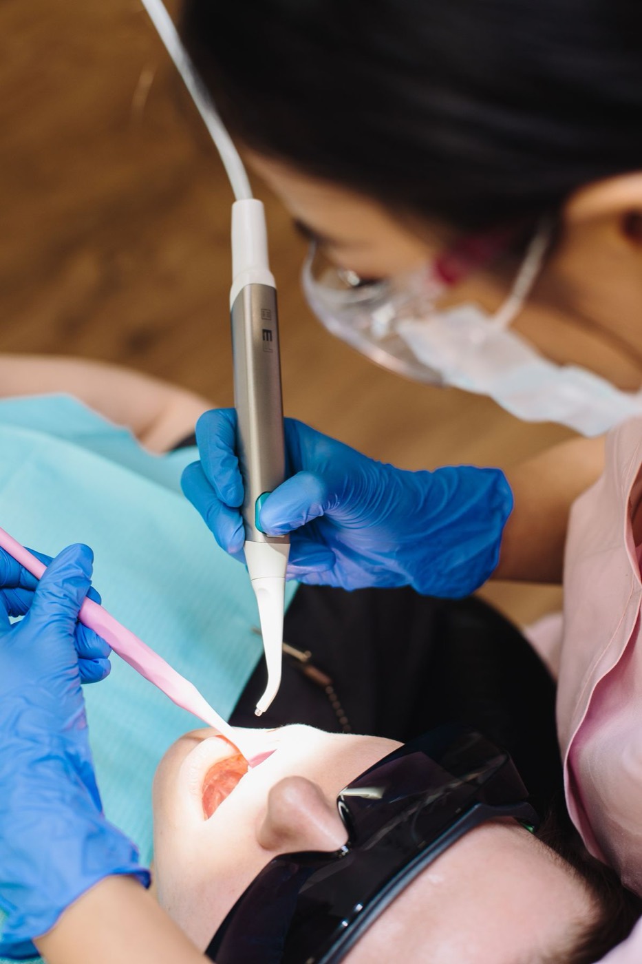 A clinician using a laser handpiece on a patient wearing protective eyewear
